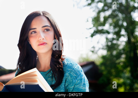 Young woman reading book in garden Banque D'Images