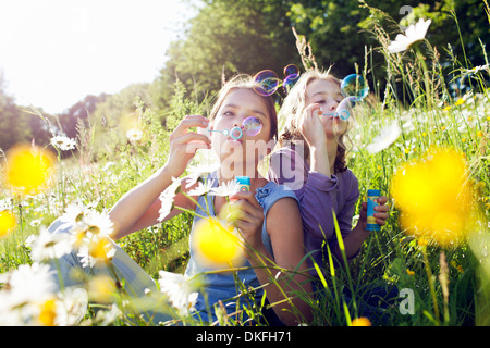 Soeurs assis dans domaine de souffler des bulles de fleurs Banque D'Images