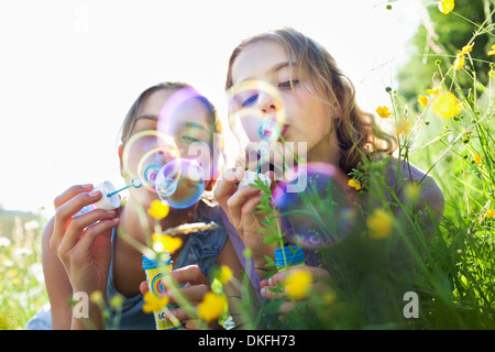 Soeurs assis dans domaine de souffler des bulles de fleurs Banque D'Images