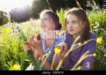 Sisters sitting manger des pommes dans le champ Banque D'Images