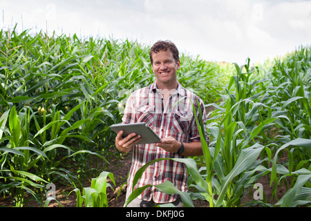 Farmer standing dans la zone de cultures using digital tablet Banque D'Images