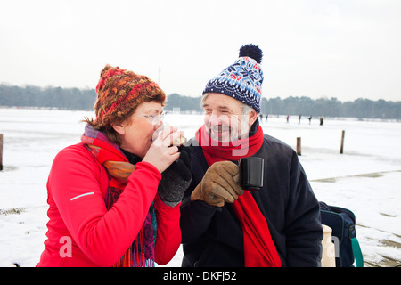 Couple having boisson chaude dans la neige Banque D'Images