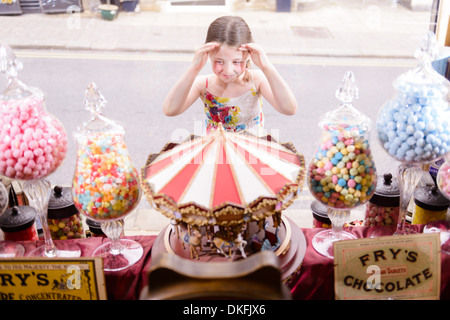 Fille à la fenêtre à travers de sweet shop Banque D'Images