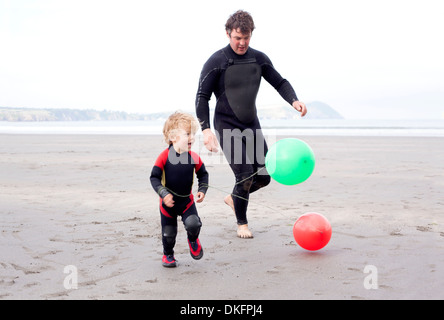 Père et fils jouant avec des ballons sur la plage Banque D'Images