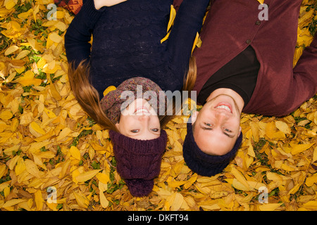 Jeune couple couché dans les feuilles d'automne Banque D'Images