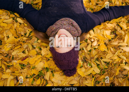 Jeune femme couchée dans les feuilles d'automne Banque D'Images