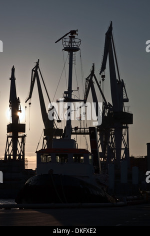 Silhouettes de grues de chantier et remorqueur dans la soirée Banque D'Images