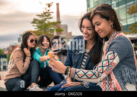 Les jeunes femmes taking self portrait photographs using smartphones Banque D'Images