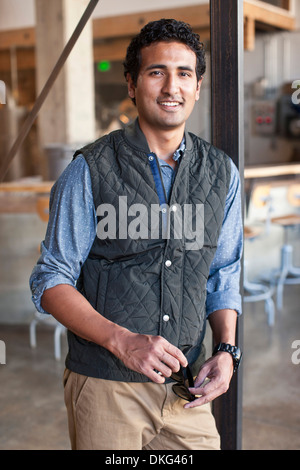 Portrait of young man leaning against wooden post