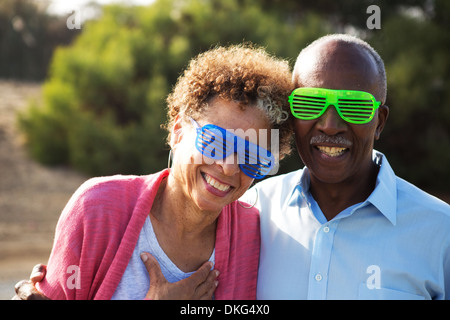 Couple portant des lunettes en plastique bleu et vert Banque D'Images