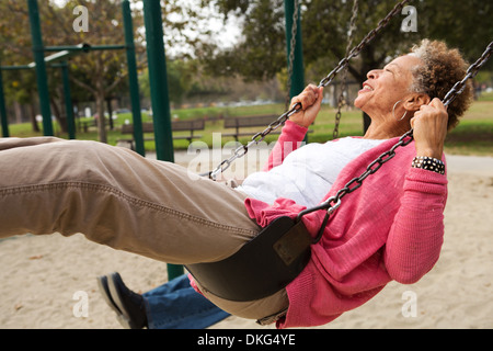 Senior woman on swing in park Banque D'Images