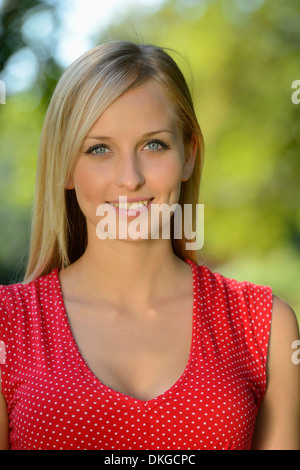Smiling young blonde woman outdoors, portrait Banque D'Images