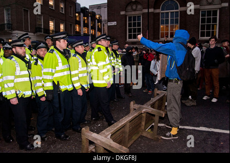 Londres, Royaume-Uni. 05/12/13. Un homme cagoulé se moque des agents de police tout en protestant contre l'extérieur de la bibliothèque de la Maison du Sénat. Les manifestants affirment que la Police Métropolitaine a utilisé une force excessive, la veille au soir lorsqu'ils ont tenté de briser une occupation de bureaux de direction au Sénat Chambre des capacités. Banque D'Images