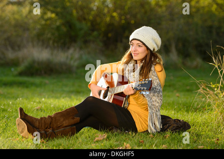Jeune femme jouant de la guitare à l'automne Banque D'Images