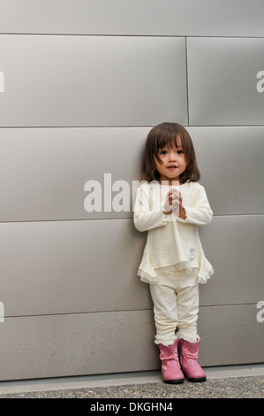 Un enfant de deux ans M. mixed race female rit tout en ayant sa photo prise. Elle a les cheveux bruns, est vêtu d'un costume blanc Banque D'Images