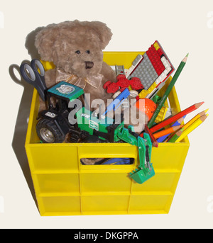 Caisse en plastique jaune - remplie de jouets pour enfants, y compris les ours, lego, tracteur, crayons de couleur - sur fond blanc Banque D'Images