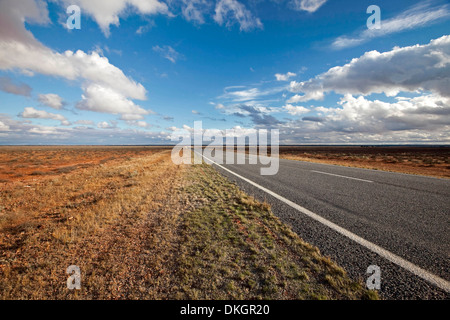 Longue route en ligne droite à travers les vastes plaines du sol rouge de outback australien qui s'étendent à l'horizon et ciel bleu près de Wentworth EN IN Banque D'Images