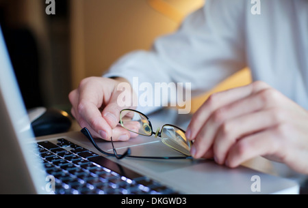 Mains d'affaires avec des lunettes sur le clavier d'ordinateur portable Banque D'Images