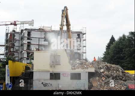 Une perforatrice pneumatique démolition d'une maison avec à l'arrière une nouvelle construction Banque D'Images