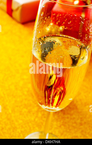 Un verre de champagne et des cadeaux sur un fond doré Banque D'Images