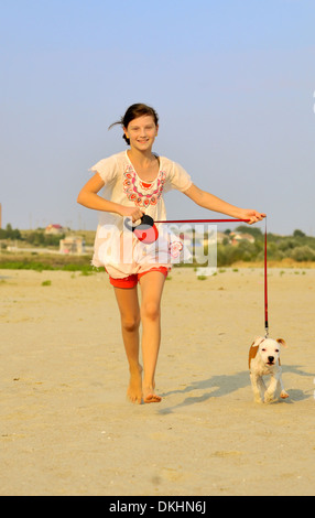 Fille courir avec son chien sur le sable un jour d'été Banque D'Images