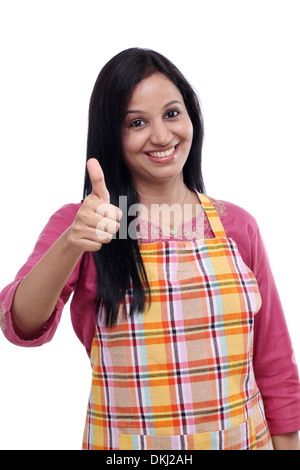 Heureux jeune femme indienne portant un tablier de cuisine et showing Thumbs up Banque D'Images