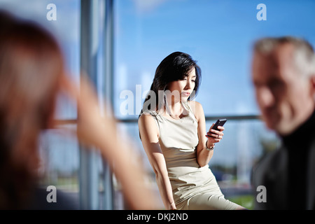 Businesswoman using cell phone in office Banque D'Images