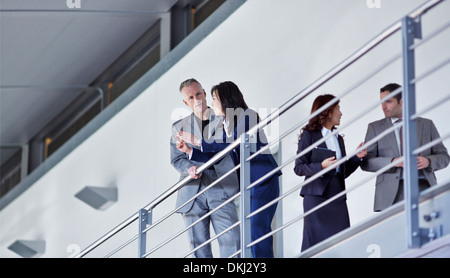 Business people talking at railing n office Banque D'Images