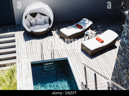 Des chaises longues sur la terrasse en bois par piscine moderne Banque D'Images