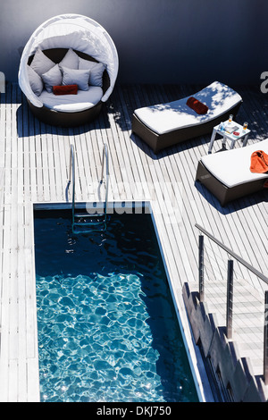 Des chaises longues sur la terrasse en bois près de la nage Banque D'Images