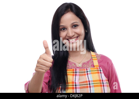 Heureux jeune femme indienne portant un tablier de cuisine et showing Thumbs up Banque D'Images