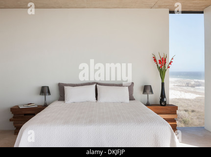 Vase de fleurs à côté du lit dans la chambre avec vue sur l'océan Banque D'Images