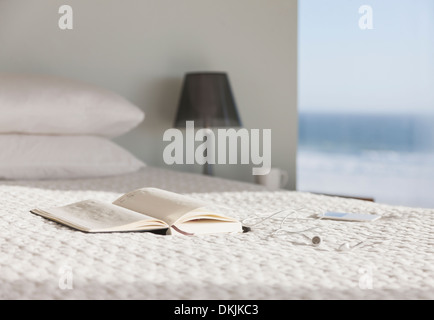 Réserver et verres sur lit dans chambre à coucher moderne avec vue sur l'océan Banque D'Images