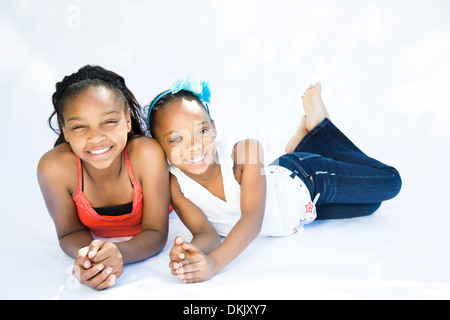 Deux heureux jeunes sœurs portant sur fond blanc Banque D'Images