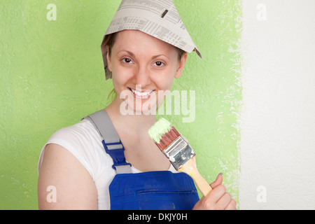 Jeune femme peindre un mur avec un pinceau Banque D'Images