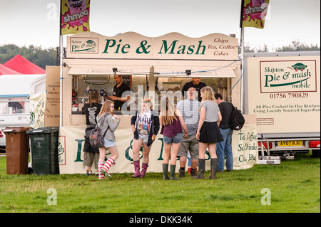 Les jeunes font la queue pour la nourriture à un 'Pie & Mash' kiosque caravane remorque au Galtres music festival. Banque D'Images