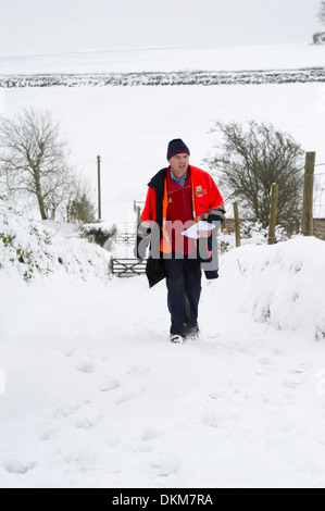 Un postier livrer du courrier à brin de maisons dans Challacombe, Devon, UK en hiver Banque D'Images