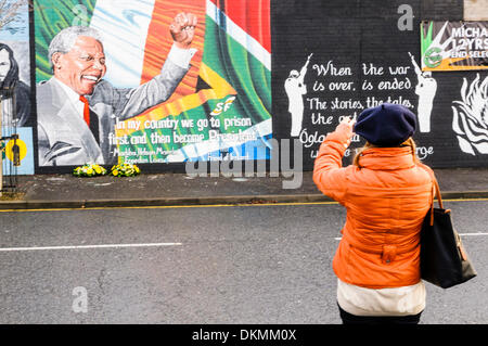 Belfast, Irlande du Nord. 7 décembre 2013 - Une femme prend une photo de la peinture murale à l'aide de Nelson Mandela un iPhone. Crédit : Stephen Barnes/Alamy Live News Banque D'Images