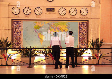 Deux messieurs à la recherche à la carte du monde avec six horloges international. Banque D'Images