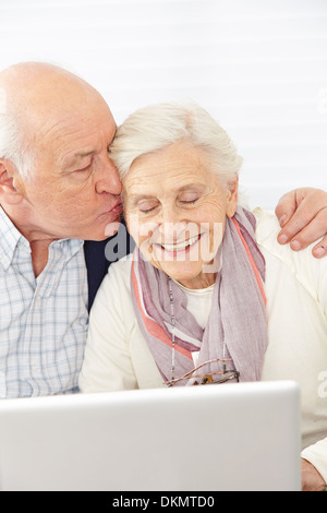 Happy man kissing smiling woman at computer Banque D'Images