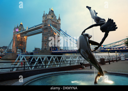 Le Tower Bridge et la statue d'une jeune fille jouant avec dauphin en St Katharine Docks de Londres. Banque D'Images