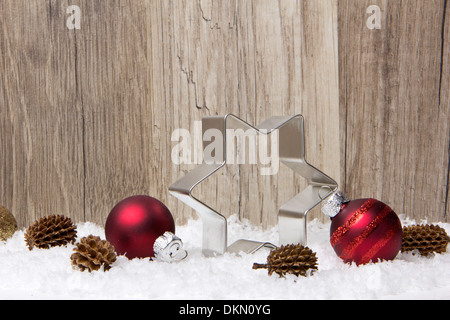 Décoration de Noël avec fond de bois, de neige, de boules de Noël, le poinsettia rouge, et des pommes de pin Banque D'Images