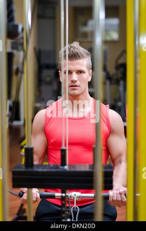 Beau jeune homme dans la salle de sport de l'exercice, l'exercice de biceps sur l'équipement Banque D'Images