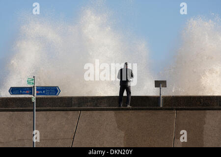 Lowestoft, UK. 06 Dec, 2013. Un photographe regarde la haute mer spectaculaire se briser contre le mur de la mer à Lowestoft. Le panneau bleu au premier plan indique que la mer mur fait partie de la mer du Nord Randonnée à Vélo et points à Lowestoft centre-ville. Elle mentionne également Ness Point qui est un peu plus loin le long de la digue, marquant l'endroit le plus à l'est au Royaume-Uni. Credit : Solveig Stibbe/Alamy Live News Banque D'Images