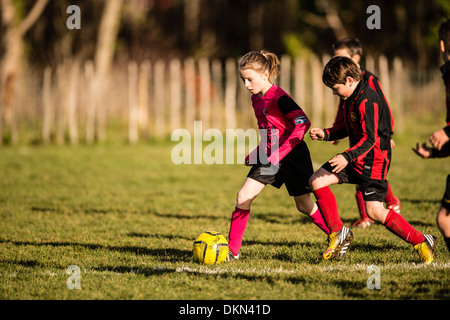 L'école primaire de garçons et de jeunes filles, jouant dans le football soccer compétitif park le samedi matin, UK Banque D'Images