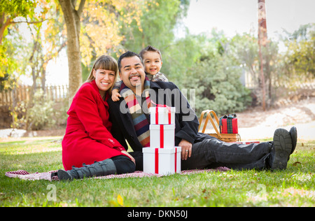 Young Mixed Race Family Enjoying Cadeaux de Noël dans le parc ensemble. Banque D'Images