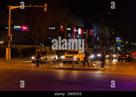 Voitures arrêtées au feu rouge que les piétons traverser la rue - Vue de nuit Banque D'Images