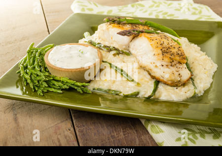 Flétan au risotto aux asperges et haricots de mer sur une plaque verte Banque D'Images