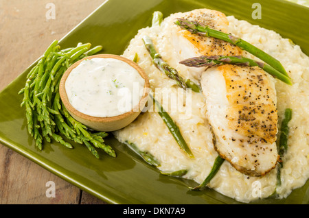 Flétan au risotto aux asperges et haricots de mer sur une plaque verte Banque D'Images