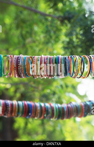 Les femmes indiennes colorés bracelets accrochés sur une ligne en face d'un temple hindou pour la décoration. L'Andhra Pradesh, Inde Banque D'Images